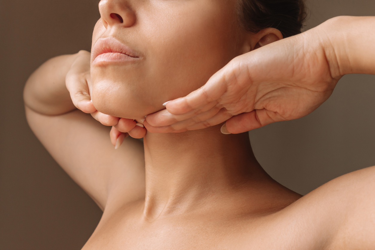 Woman touching her smooth chin and jawline, representing chin laser hair removal.